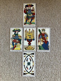 four tarot cards on a carpet