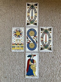 four tarot cards on a carpet